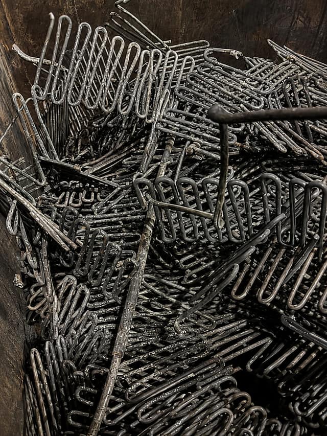 Bent wire and rod offcuts piled in a wooden storage bin.